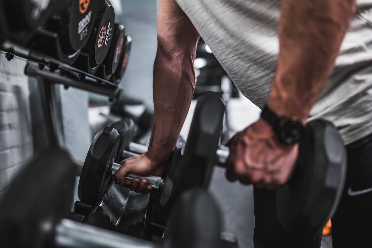 Homme saisissant des haltères en salle de musculation, le meilleur exercice pour perdre du ventre